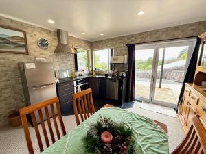 a kitchen with a table and a kitchen with a refrigerator at Cosy Raglan Studio - Walk to Beach and Village - Roberts St - Studio Downstairs in Raglan +12 photos