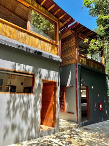 a house with a wooden door and a balcony at Deck Picinguaba Pousada in Picinguaba