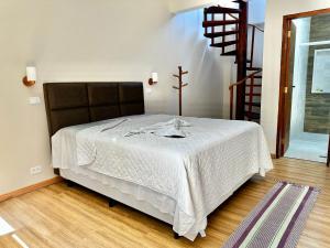 a bedroom with a large bed with a white blanket at Deck Picinguaba Pousada in Picinguaba