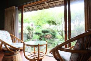 a room with a glass table and chairs in front of a window at Guest House Ilonggo in Tsu