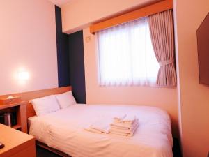 a hotel room with a bed with towels on it at Asahikawa Sun Hotel in Asahikawa