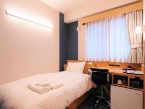 a bedroom with a bed and a desk with a computer at Asahikawa Sun Hotel in Asahikawa