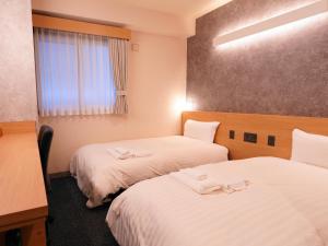 a hotel room with two beds and a window at Asahikawa Sun Hotel in Asahikawa