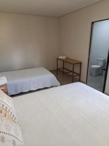 a bedroom with two beds and a table with a toilet at Espaço Real in Manhã +4 photos
