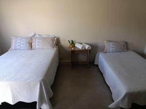 a bedroom with two beds and a nightstand with a table at Espaço Real in Manhã