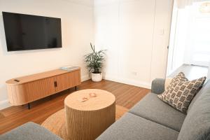 a living room with a couch and a flat screen tv at Soluna House in Byron Bay