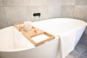 a bathroom with a white tub with a wooden tray on it at Soluna House in Byron Bay +16 photos
