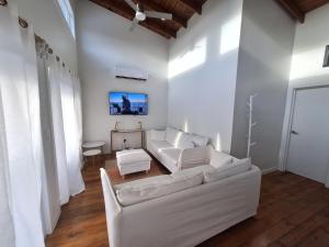 a white living room with a white couch and a tv at Island Time house in Utila