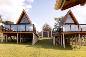 two story houses with glass windows on the grass at Pousada Flor do Campestre in Urubici