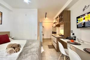 a bedroom with a large bed and a kitchen at Studio Congonhas I SP Expo I Morumbis & Interlagos in São Paulo