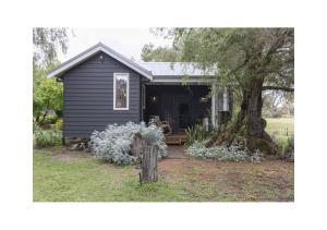 a small black house with a tree in the yard at Rústica Estate in Quindalup