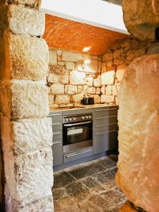 a kitchen with a stove and a stone wall at Lovingly Restored Half-Timbered House From 1684 in Großschönau