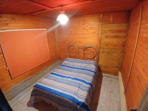 a small bedroom with a bed in a wooden room at Hospedaje Abiel in El Mollar