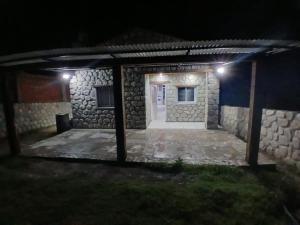 a stone house with a white door at night at Hospedaje Abiel in El Mollar