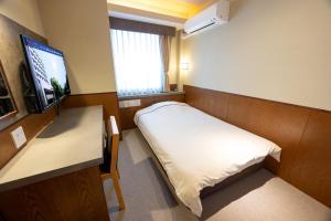 a room with a bed and a desk and a television at Okayama View Hotel in Okayama