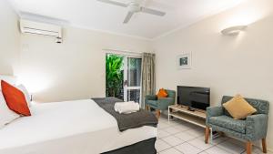 a bedroom with a bed and two chairs and a television at Trinity Beach Pacific in Trinity Beach
