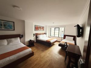 a hotel room with two beds and a desk at Hotel Splendor by Friends Company in Bogotá