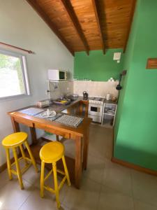 a kitchen with a wooden table and two yellow stools at La Candelaria - Casas de Campo - in Sierra de la Ventana
