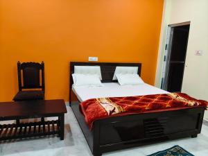 a bedroom with a bed with an orange wall at Sri Narayan Home Stay in Ayodhya