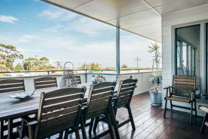 a porch with a table and chairs on a balcony at Anglesea by Bangalay in Shoalhaven Heads