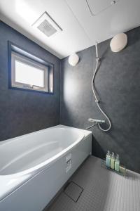 a bathroom with a white tub and a window at The Crane Sanctuary Kamifurano in Kami-furano