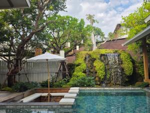 a swimming pool with an umbrella and a fountain at Baan Prod Pool Villa Chiang Mai in Chiang Mai