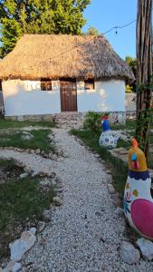 a small house with a thatch roof and a gravel path at Cabaña 2 Los Gallitos Ecolodge in Sacalum