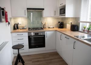 a kitchen with white cabinets and a black oven at Justina's House in East Kilbride