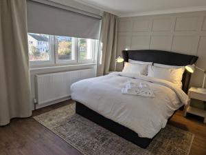 a bedroom with a large bed with white sheets and a window at Justina's House in East Kilbride