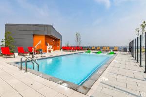 a swimming pool with red chairs and a building at Penthouse Retreat with Rooftop Pool Explore Silver Spring & Washington DC in Silver Spring