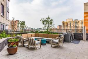 a patio with a couch and chairs and a tv on a roof at Penthouse Retreat with Rooftop Pool Explore Silver Spring & Washington DC in Silver Spring