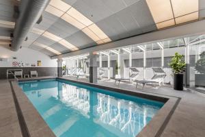 a swimming pool in a building with chairs and tables at Clarion Suites Gateway in Melbourne