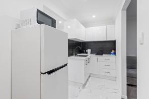 a white kitchen with a refrigerator and a sink at Forest view guesthouse in Runcorn