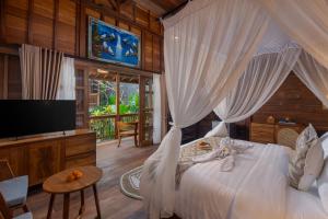 a bedroom with a bed and a television in a room at Kirani House - Joglo Villa Bali in Darmasaba +16 photos