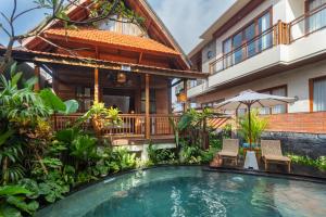 a villa with a swimming pool in front of a house at Kirani House - Joglo Villa Bali in Darmasaba