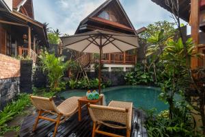 a patio with two chairs and a table with an umbrella at Kirani House - Joglo Villa Bali in Darmasaba