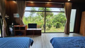 a bedroom with a bed and a desk and a large window at Cafe cắm trại Đồng Gió Phước Hải in Xã Long Mỹ