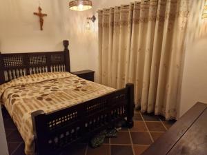a bedroom with a bed with curtains and a cross on the wall at Villa Alejandra in Quebrada Vieja +6 photos