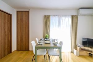 a dining room table with white chairs and a television at Chill Place 120 Ayase in Tokyo