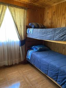 zwei Etagenbetten in einer Hütte mit Fenster in der Unterkunft Cabañas Anny 1 in Linares