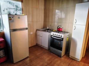eine Küche mit Kühlschrank, Herd und Spüle in der Unterkunft Cabañas Anny 1 in Linares