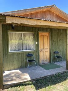 Zwei Stühle stehen vor einem Haus mit einer Tür. in der Unterkunft Cabañas Anny 1 in Linares