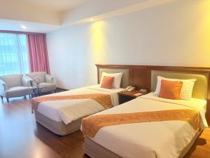 a hotel room with two beds and a chair at Tai Pan Hotel in Bangkok