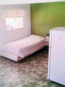 a small bedroom with a bed and a refrigerator at Lo de Facu in Puerto Pirámides