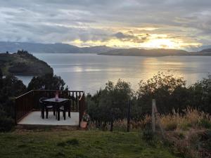 a table with a drink on it sitting on a porch overlooking a lake at Munay Tota Signature in Aquitania +8 photos