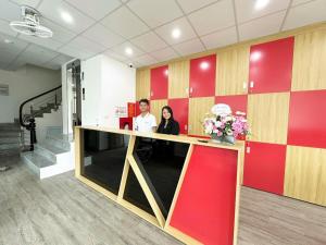 two people standing at a counter in an office at Ha Noi Capsule Station Hostel in Hanoi