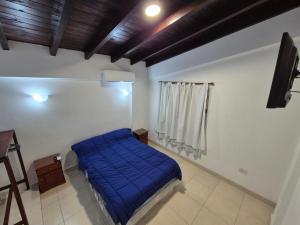 a bedroom with a bed with a blue blanket at Departamentos Blazu Cafayate in Cafayate