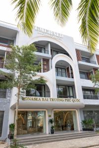 a facade of a building with a palm tree at Emerald Boutique Hotel Phú Quốc in Phú Quốc