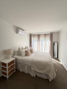 a white bedroom with a bed and a window at Sarah's Guest House in Havelock North