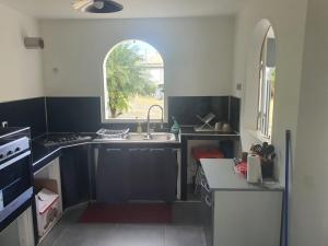 a kitchen with a sink and an arch window at Villa familiale pensé pour vous in Les Abymes